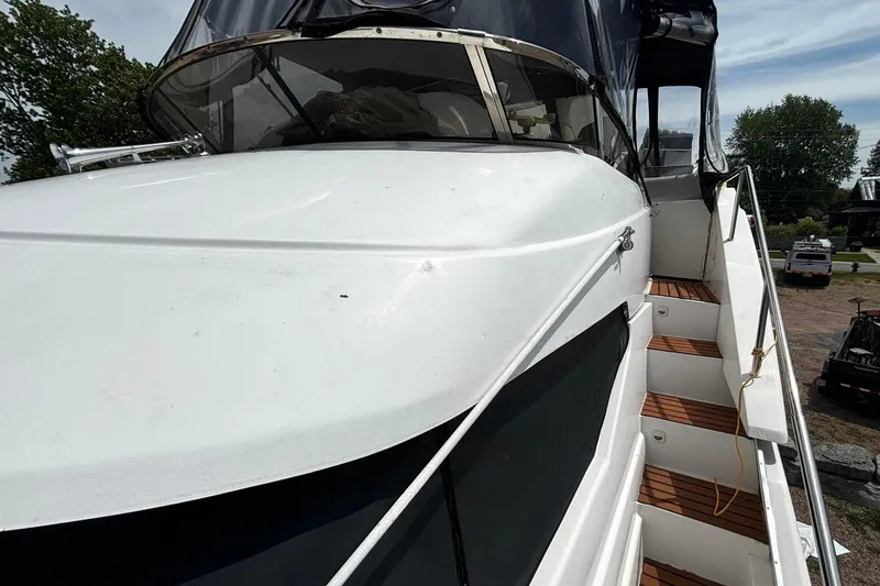 Slide: The Image of 1999 Silverton 453 Motor Yacht with white exterior and wooden steps, docked outdoors. - 35