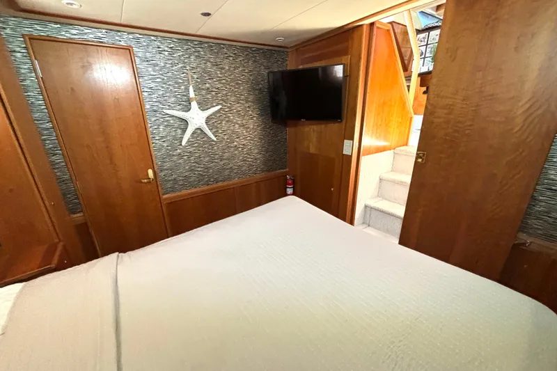 Slide: The Image of 1999 Silverton 453 Motor Yacht bedroom with wood paneling, TV, and starfish decor. - 49