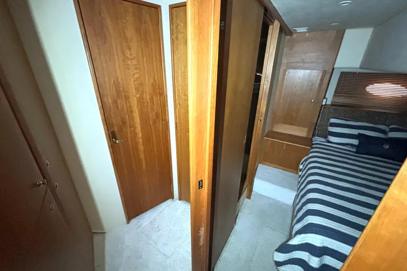 Slide: The Image of Interior of 1999 Silverton 453 Motor Yacht with wooden doors and striped bedding. - 53