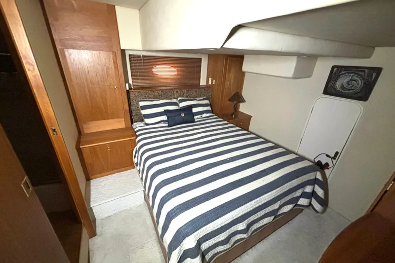 Slide: The Image of Bedroom interior of 1999 Silverton 453 Motor Yacht with striped bedding and wooden cabinetry. - 54