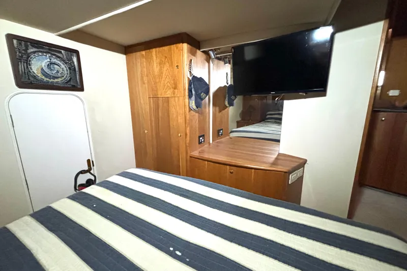 Slide: The Image of Interior of 1999 Silverton 453 Motor Yacht with striped bedding and wooden cabinetry. - 55