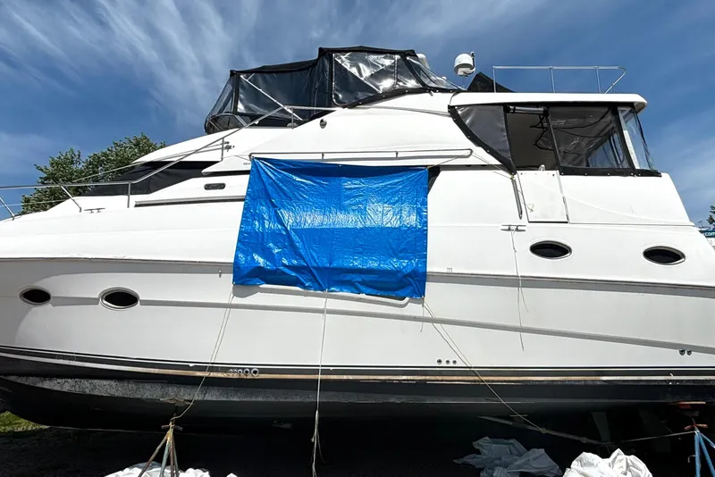 Slide: The Image of 1999 Silverton 453 Motor Yacht with blue tarp, docked under clear sky. - 6