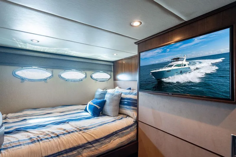 Slide: The Image of Luxurious yacht bedroom with striped bedding, porthole windows, and a wall-mounted TV displaying a boat. - 102