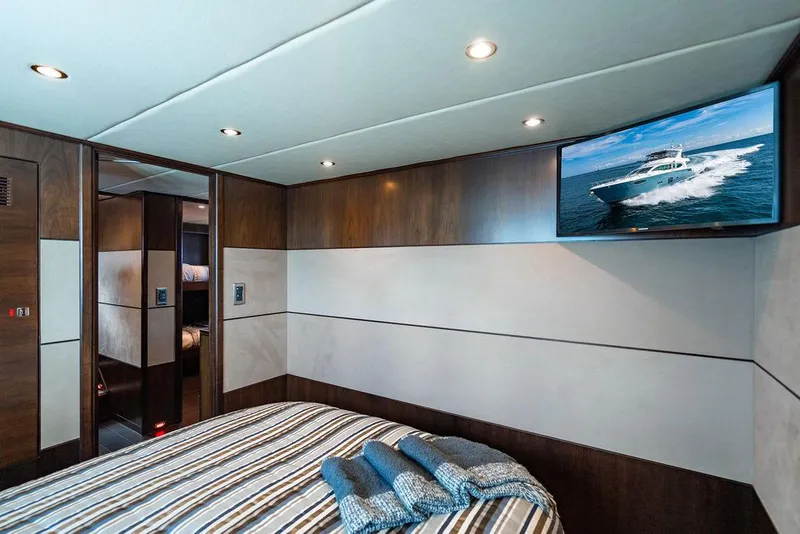 Slide: The Image of Luxurious yacht bedroom interior with striped bedding, wall-mounted TV, and modern wood paneling. - 94