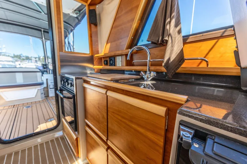 Slide: The Image of Interior of 2015 Cutwater 28 boat featuring a wooden kitchen with sink and stove. - 8