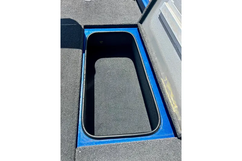 Slide: The Image of Open storage compartment in 2017 Triton 18 C TX boat, featuring blue trim and carpeted interior. - 34