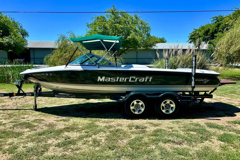 Slide: The Image of 2002 MasterCraft ProStar 197 boat on trailer, green canopy, parked on grass. - 1