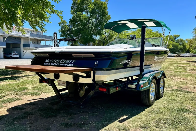 Slide: The Image of 2002 MasterCraft ProStar 197 boat on trailer, parked outdoors under a sunny sky. - 3
