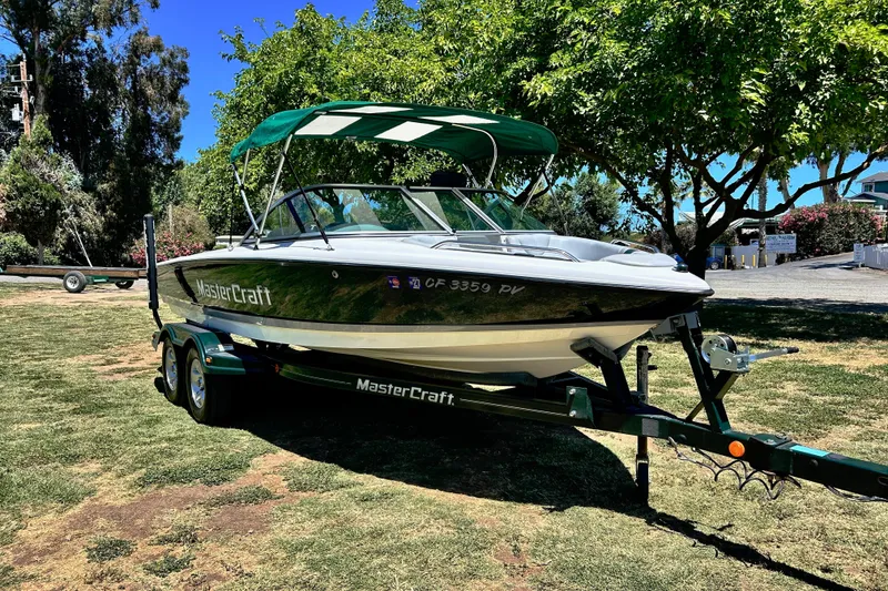 Slide: The Image of 2002 MasterCraft ProStar 197 boat on trailer, parked on grass under trees. - 4