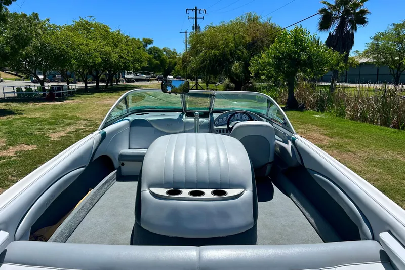 Slide: The Image of 2002 MasterCraft ProStar 197 boat interior with gray seating, dashboard, and lush green surroundings. - 7