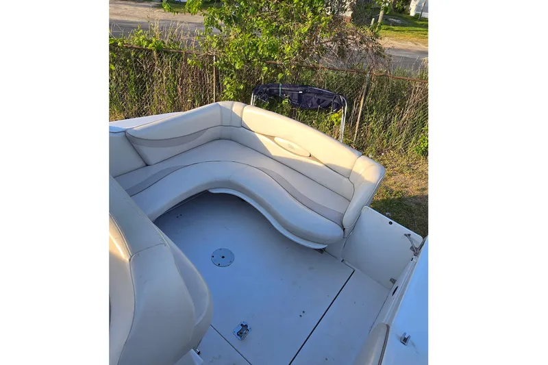 Slide: The Image of 1999 Four Winns 258 Vista boat with curved seating, outdoor setting. - 10