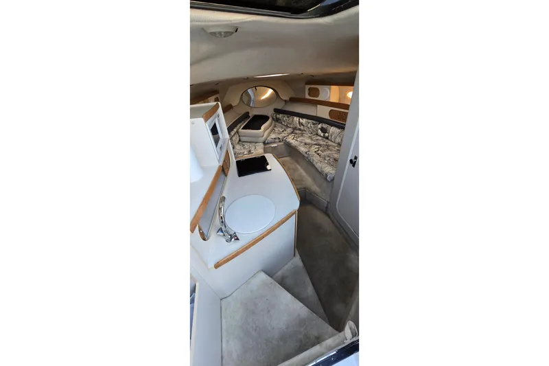 Slide: The Image of Interior of 1999 Four Winns 258 Vista boat, featuring cozy seating and compact kitchenette. - 12