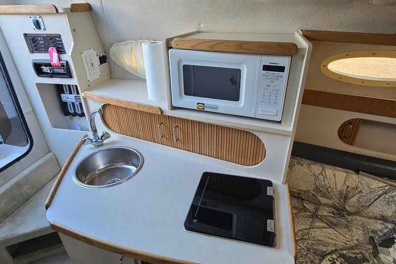 Slide: The Image of Compact kitchenette in a 1999 Four Winns 258 Vista boat with sink, microwave, and stove. - 16