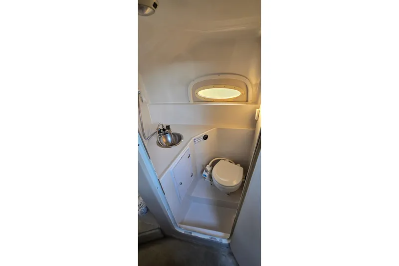 Slide: The Image of 1999 Four Winns 258 Vista boat bathroom with sink, toilet, and porthole window. - 17