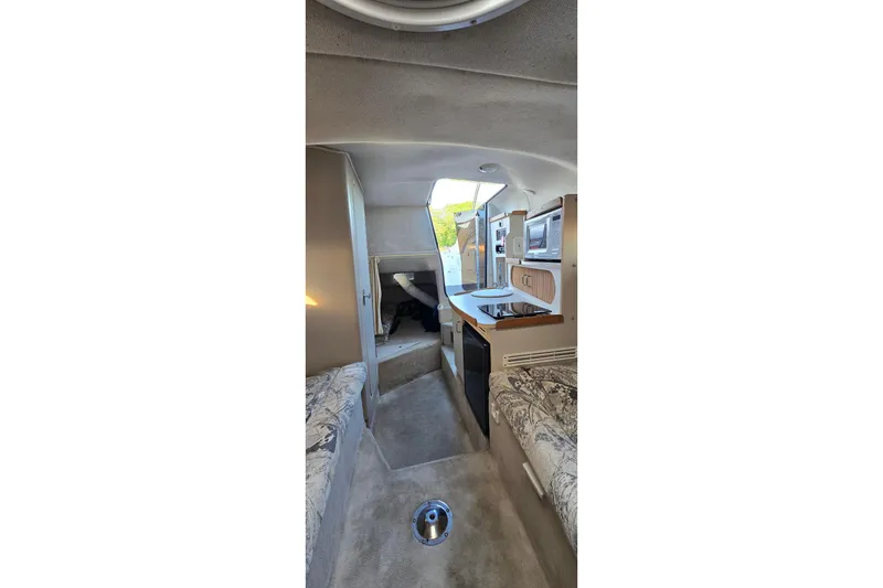 Slide: The Image of Interior of 1999 Four Winns 258 Vista boat, featuring compact kitchen and seating area. - 21