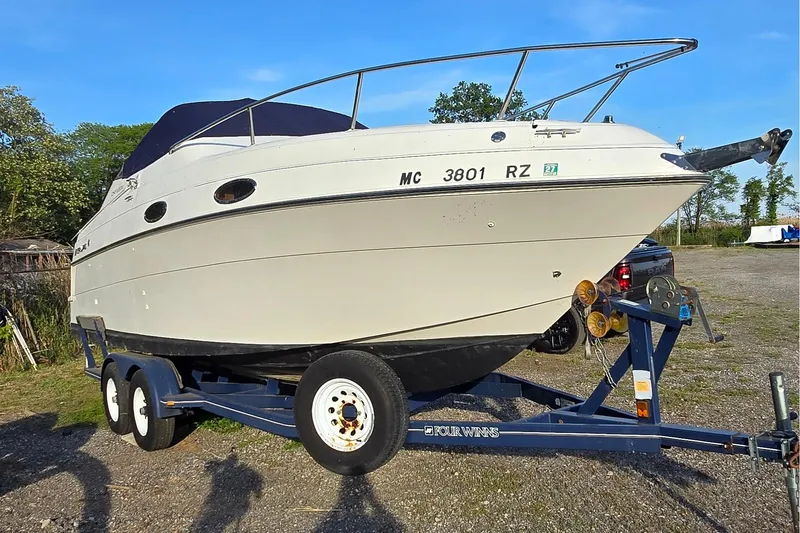 Slide: The Image of 1999 Four Winns 258 Vista boat on trailer, parked outdoors under clear blue sky. - 3