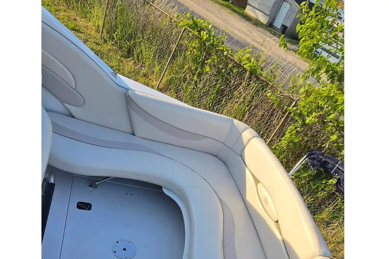 Slide: The Image of 1999 Four Winns 258 Vista boat interior with white seating, surrounded by greenery. - 6