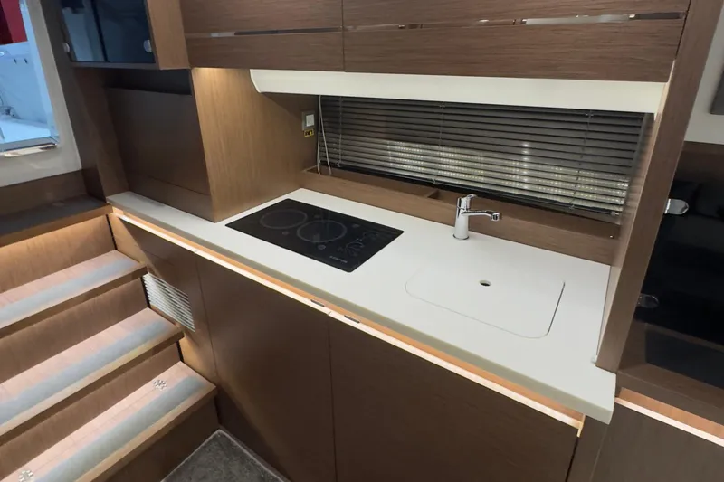 Slide: The Image of Modern kitchen area in a 2021 Jeanneau Leader 12.5 WA boat, featuring a sleek cooktop and sink. - 29