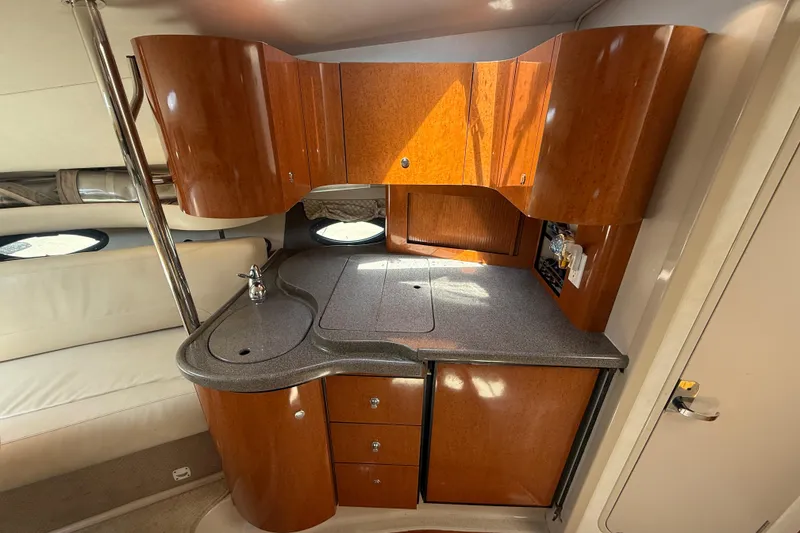 Slide: The Image of Interior of a 2001 Doral 330se boat featuring a compact wooden kitchenette. - 24