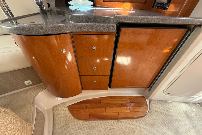 Slide: The Image of Interior of a 2001 Doral 330se boat featuring wooden cabinetry and a compact kitchenette. - 25