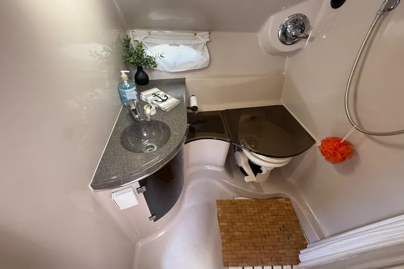 Slide: The Image of Compact bathroom in a 2001 Doral 330se boat with sink, toilet, and shower amenities. - 31