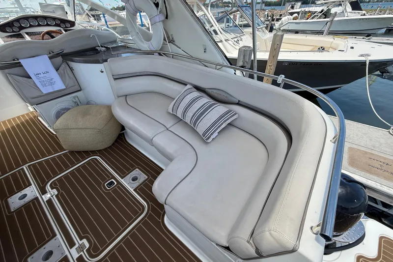 Slide: The Image of 2001 Doral 330se boat interior with cushioned seating, striped pillow, and wooden flooring at marina. - 6