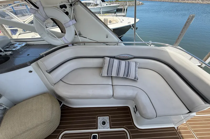 Slide: The Image of 2001 Doral 330se boat interior with cushioned seating and striped pillow by the water. - 7