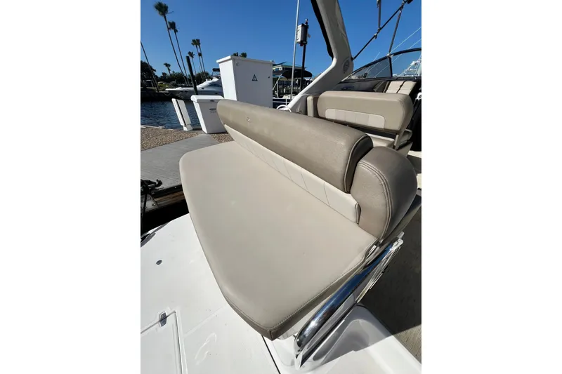 Slide: The Image of 2015 Regal 30 Express boat seating area with beige upholstery and marina backdrop. - 13