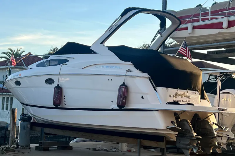 Slide: The Image of 2015 Regal 30 Express boat docked, covered with black tarp, American flag visible. - 5