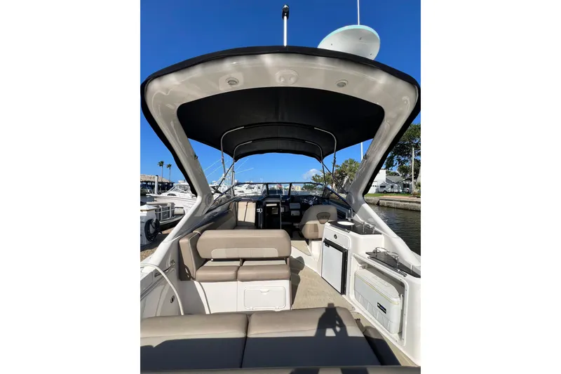 Slide: The Image of 2015 Regal 30 Express boat interior with seating and canopy, docked under clear blue sky. - 7