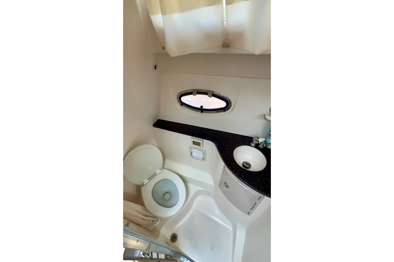 Slide: The Image of 2015 Regal 30 Express boat bathroom with toilet, sink, and porthole window. - 29