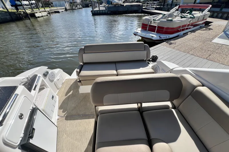 Slide: The Image of 2015 Regal 30 Express boat interior with beige seating, docked near water. - 9