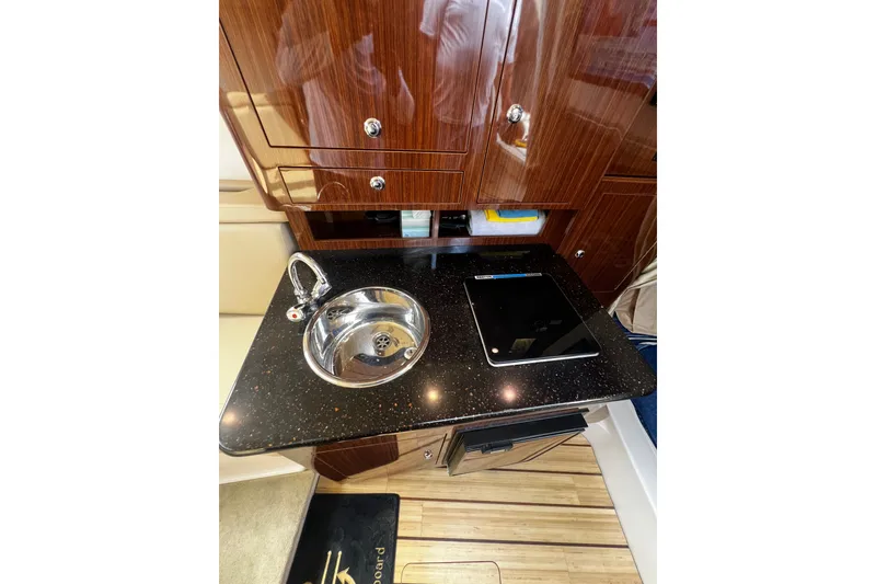 Slide: The Image of 2015 Regal 30 Express yacht interior with sleek kitchenette, featuring sink and cooktop. - 24