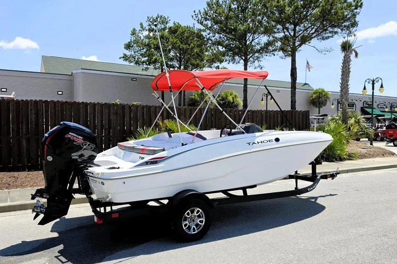 Slide: The Image of 2026 Tahoe T18 boat with red canopy on trailer, parked outdoors. - 1