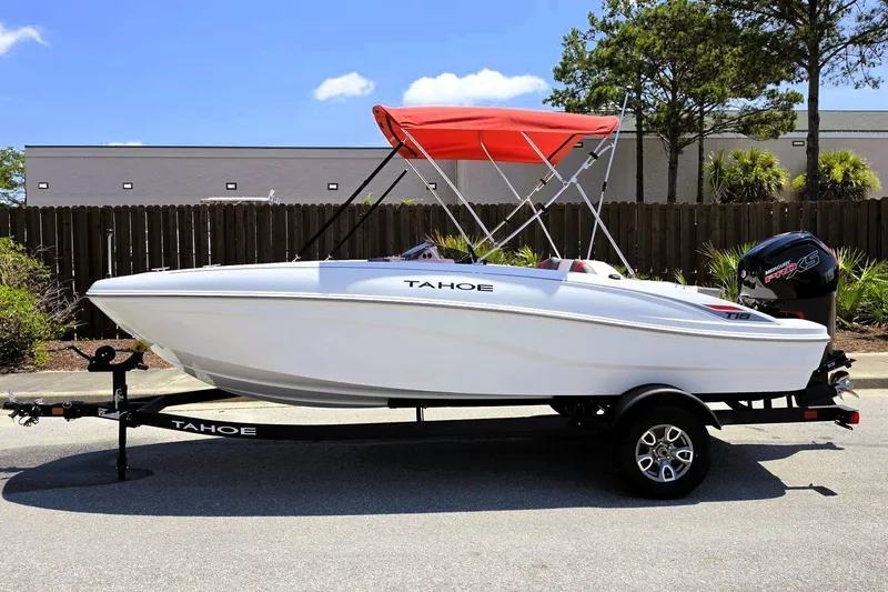 Slide: The Image of 2026 Tahoe T18 boat with red canopy on trailer, parked outdoors. - 9