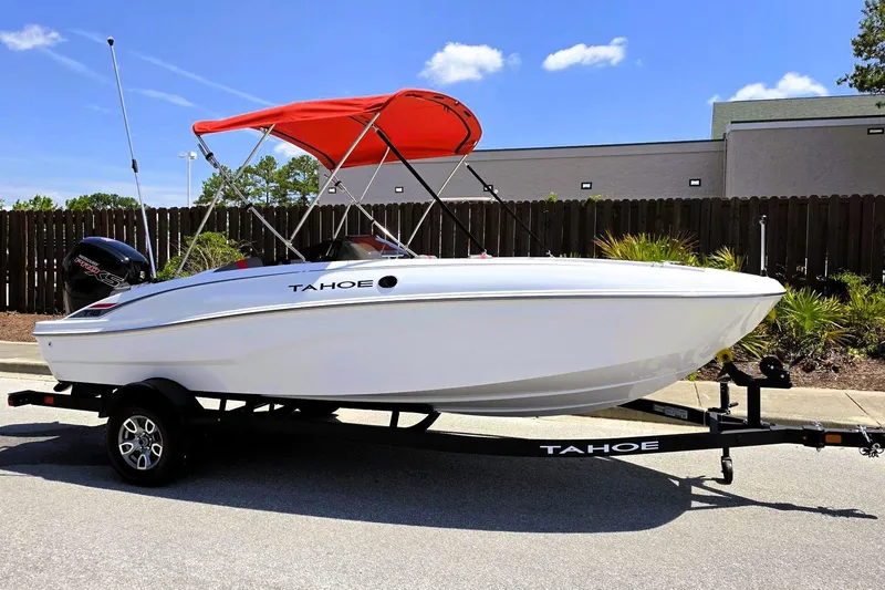 Slide: The Image of 2026 Tahoe T18 boat with red canopy on trailer, parked outdoors. - 5