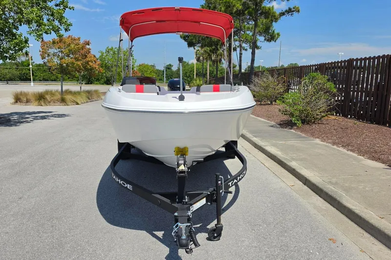 Slide: The Image of 2026 Tahoe T18 boat with red canopy on trailer, parked on sunny street. - 8