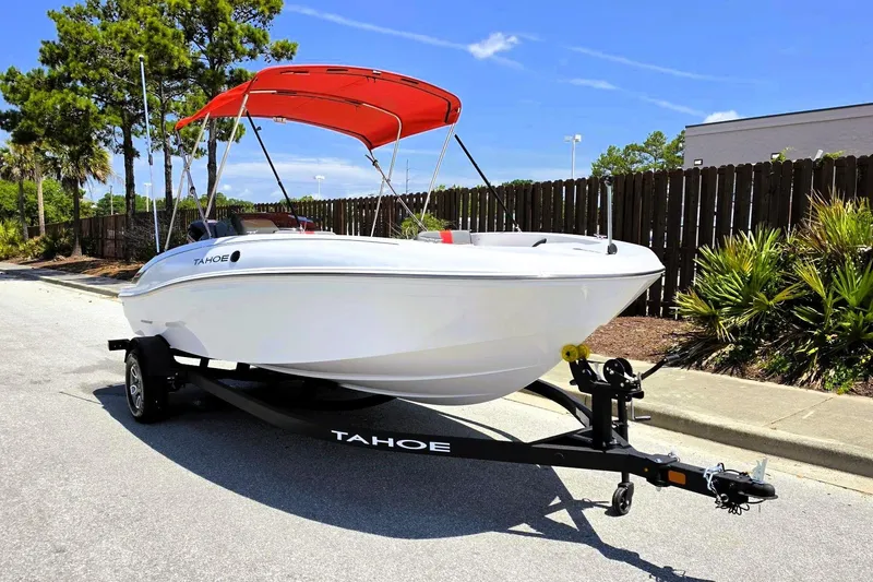 Slide: The Image of 2026 Tahoe T18 boat with red canopy on trailer, parked outdoors. - 6