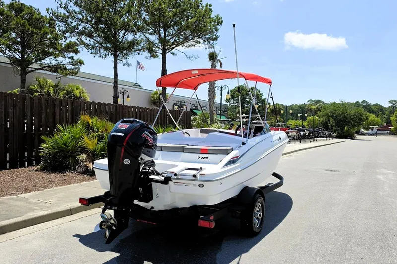 Slide: The Image of 2026 Tahoe T18 boat with red canopy on trailer, parked outdoors. - 3