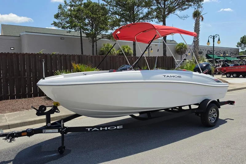 Slide: The Image of 2026 Tahoe T18 boat with red canopy on trailer, parked outdoors. - 10