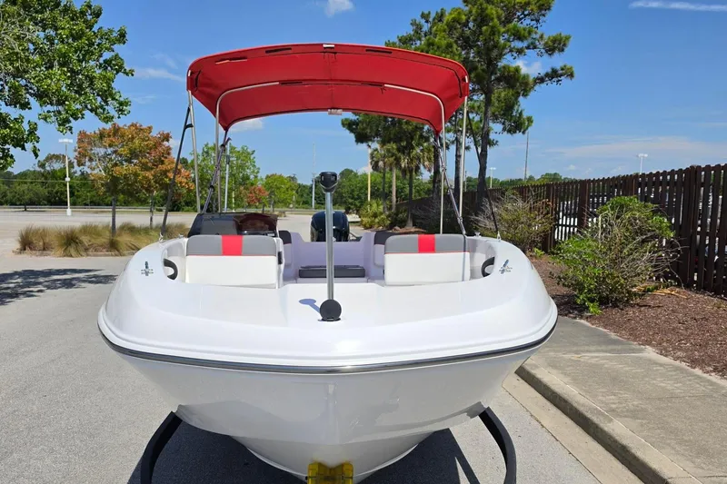 Slide: The Image of 2026 Tahoe T18 boat with red canopy, parked outdoors on a sunny day. - 7