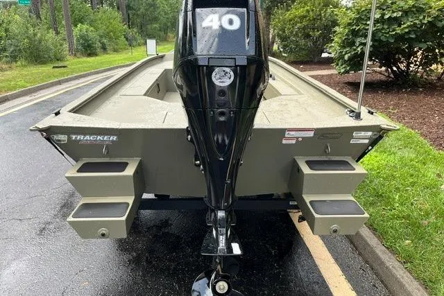 Slide: The Image of 2026 Tracker Grizzly 1654 T Sportsman boat with 40 HP motor, parked on wet pavement. - 2