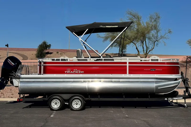 The Image of 2026 Sun Tracker Fishin' Barge 22 DLX pontoon boat with canopy on trailer. - 0