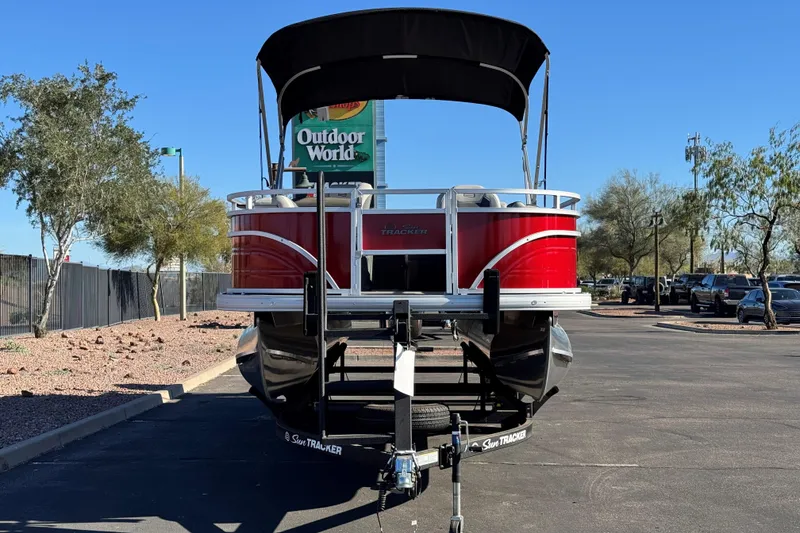 Slide: The Image of 2026 Sun Tracker Fishin' Barge 22 DLX pontoon boat parked outdoors. - 2