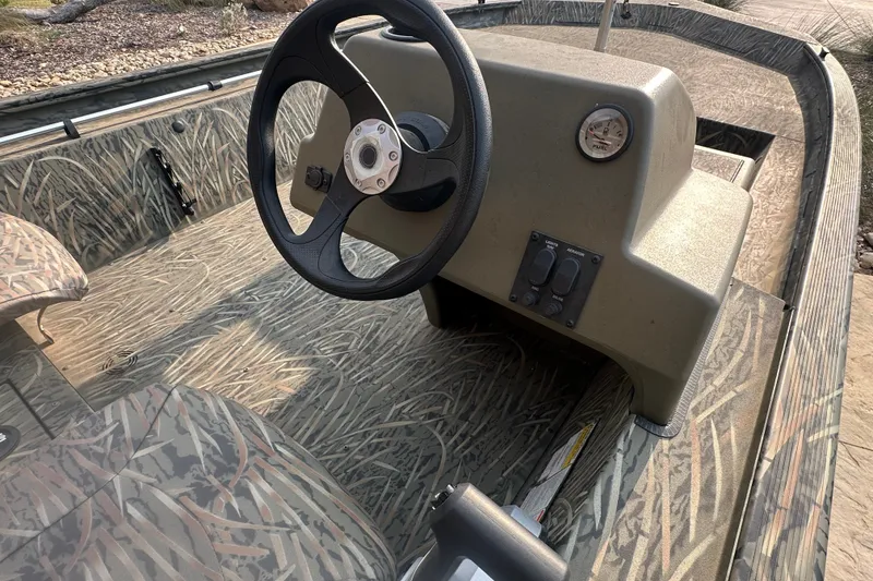 Slide: The Image of 2026 Tracker Grizzly 1754 SC boat interior with steering wheel and camo design. - 33
