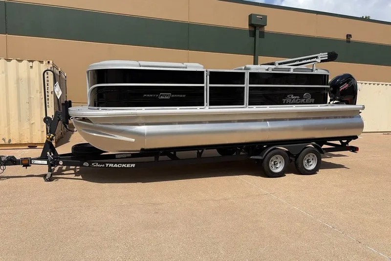 Slide: The Image of 2026 Sun Tracker Party Barge 20 DLX pontoon boat on trailer, parked outdoors. - 3