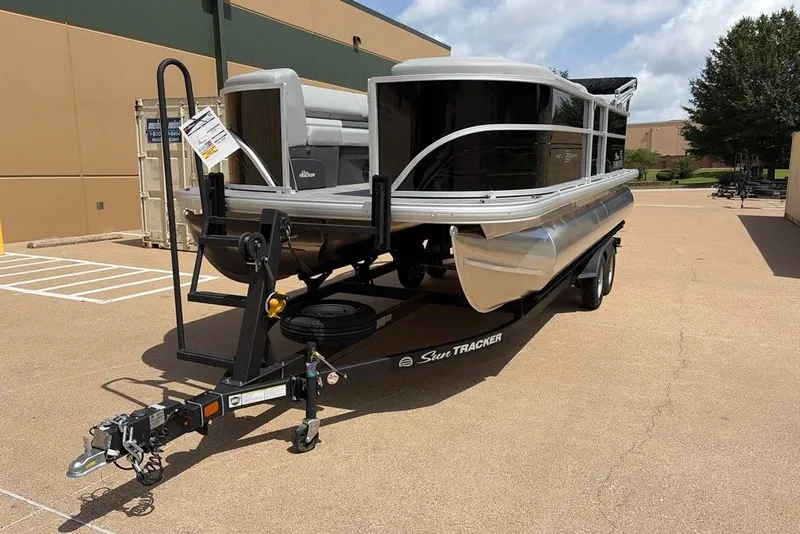 The Image of 2026 Sun Tracker Party Barge 20 DLX pontoon boat on trailer in parking lot. - 0