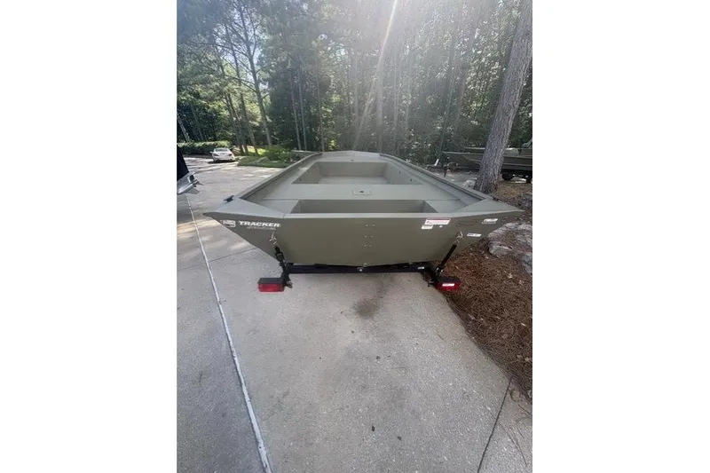 Slide: The Image of 2026 Tracker Grizzly 1754 Utility boat on trailer in wooded driveway. - 3