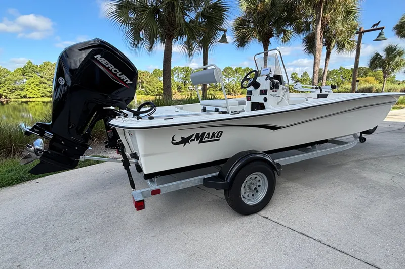 Slide: The Image of 2026 Mako Pro Skiff 17 CC boat on trailer, parked near palm trees. - 2