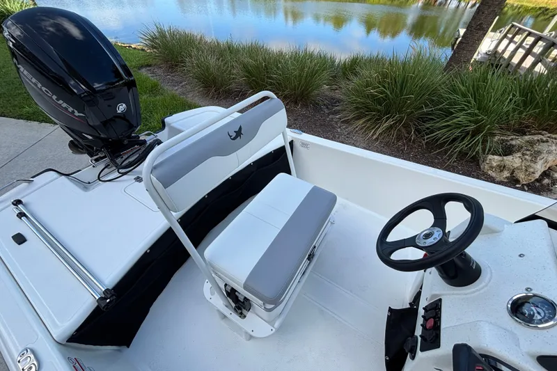 Slide: The Image of 2026 Mako Pro Skiff 17 CC boat interior with Mercury engine by a lake. - 11